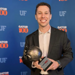 A picture of Scott Bartnick holding his Gator100 award.